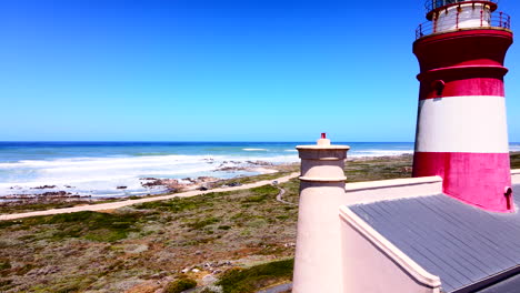 Agulhas-lighthouse-on-treacherous-rocky-coastline,-aerial-fly-by