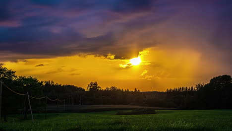 Goldenes-Licht-Der-Sonne-Strömt-Unten-Vorbei-An-Grauen-Schauerwolken,-Orangefarbenes-Licht-über-Die-Waldwiese