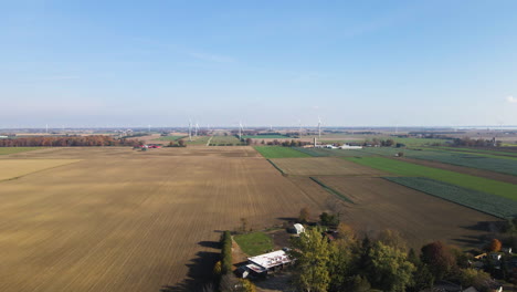 Drohne-Drängt-über-Bewaldete-Bauernhäuser-Mit-Großen-Getreidefeldern-Und-Wolkenschatten-An-Land