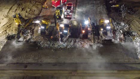 Bagger-Mit-Verschiedenen-Werkzeugen-Zerstören-Nachts-Brücke,-Luftaufnahme