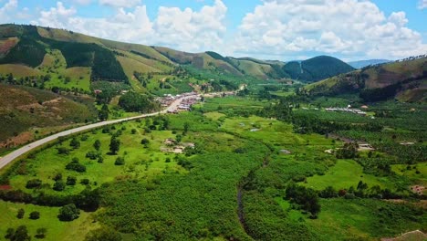 African-Landscape-With-Road,-Lush-Green-Fields-And-Mountains-In-Uganda---drone-shot