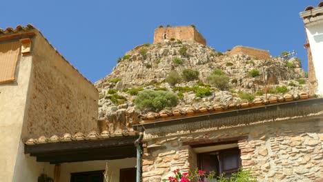 Detail-of-a-residence-built-with-stones-and-a-castle-in-the-background-in-Old-Town-Borriol,-Spain