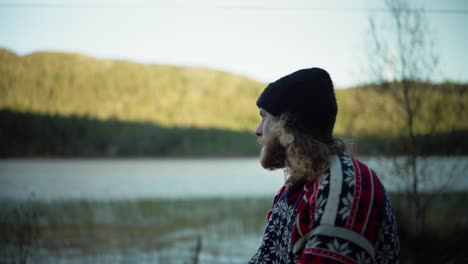 Norwegian-Guy-With-Long-Hair-Drinking-Coffee-Near-Mountain-Lake