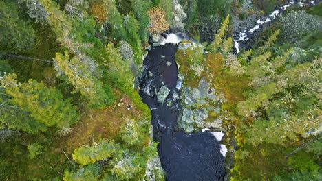 Vista-Aérea-Del-Agua-Que-Fluye-Hacia-Las-Cascadas-Dentro-Del-Bosque-Durante-El-Otoño-En-Suecia