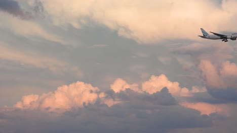 -Airplane-from-branded-company-flying-over-a-sky-with-some-white-clouds,-during-sunset