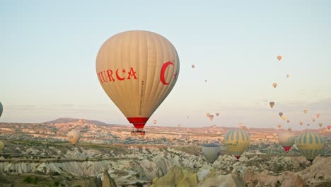 Colourful-hot-air-balloon-drift-over-red-valley-rocky-landscape