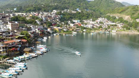 Aerial-tracking-follows-boat-exiting-harbor-of-Lake-Atitlan-Guatemala-out-on-a-new-adventure