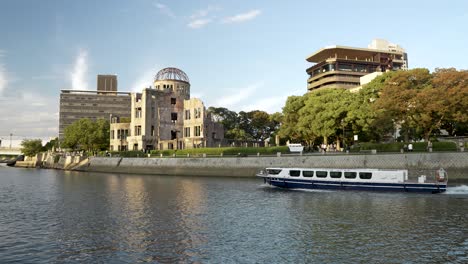 Ferry-Boat-Sailing-Past-Atomic-Bomb-Dome-In-Hiroshima-Along-Motoyasu-River-On-Sunny-Afternoon