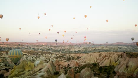 Hot-air-balloon-sunrise-flight-red-valley-rocky-landscape