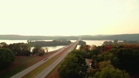 Autumn-dusk-on-Tennessee-River-Bridge,-aerial-ascend-from-trucker-Logistics-business