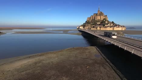 People-walking-along-bridge-with-Mont-Saint-Michel-in-background,-Normandy-in-France