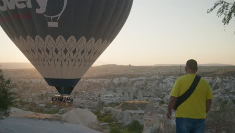 El-Hombre-Observa-A-Los-Turistas-Descender-Lentamente-En-Globo-Aerostático-Por-El-Valle-De-Goreme.