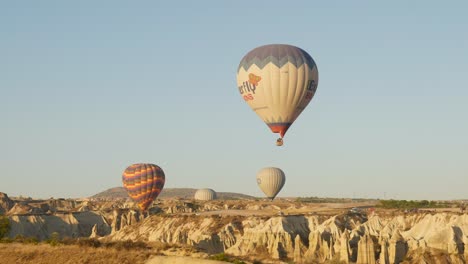Hot-air-ballon-descend-over-rocky-terrain-love-valley-fairy-chimneys