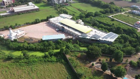 Aerial-drone-camera-moving-to-the-side,-showing-a-solar-system-above-the-hostel,-and-a-road-in-front-of-it