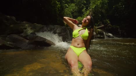 At-a-Caribbean-waterfall,-a-bikini-clad-young-girl-enjoys-the-scenic-beauty
