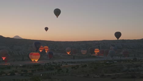 Heißluftballons-Erhellen-Die-Dunkle-Landschaft-Am-Frühen-Morgen-Beim-Abheben