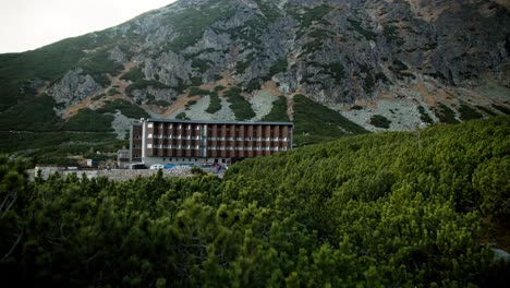 Push-in-along-coniferous-shrubs-reveals-modern-hotel-at-mountain-base-in-Sliezsky-Dom,-High-Tatras-Slovakia