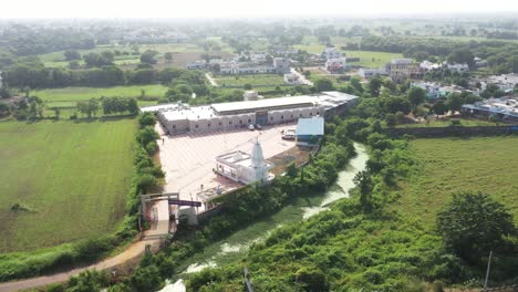 Aerial-drone-camera-moving-to-the-side,-with-low-rise-buildings-surrounded-by-fields