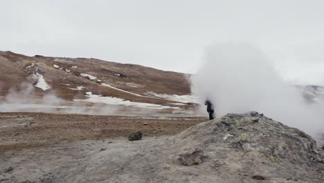 Tourist-walk-through-white-vapor-cloud-from-active-steam-vent,-Iceland