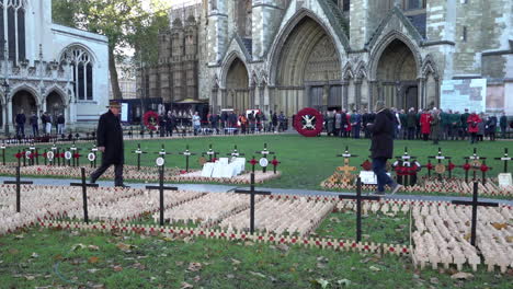 In-slow-motion-people-walk-past-thousands-of-tiny-wooden-crosses-and-large-wreaths-made-of-red-poppies,-on-Armistice-Day-at-the-Garden-of-Remembrance-outside-Westminster-Abbey