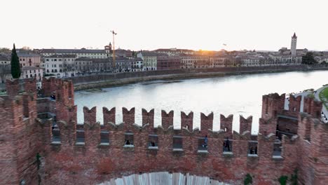 Forward-Aerial-Drone-shot-of-Castelvecchio's-Bridge-at-Golden-hour,-close-to-Sunset-time,-With-no-recognizable-people-walk-on-the-bridge-with-birds-flying-at-the-end-of-the-clip