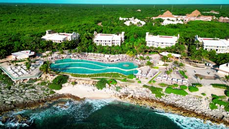 Trs-Resort-In-Tulum,-Mexiko,-Schwenk-Drohnenansicht-Des-Infiniti-Pools-Mit-Wellen,-Die-Auf-Die-Felsen-Schlagen