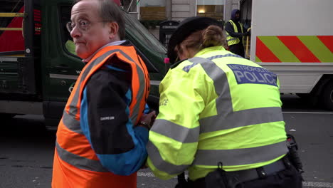 Eine-Polizistin-Eskortiert-Einen-Mit-Handschellen-Gefesselten-Und-Festgenommenen-älteren-Menschen,-Der-Gerade-Öldemonstranten-Von-Der-Straße-In-Whitehall-Abhält