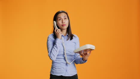 Asian-woman-conducts-remote-call-on-her-landline-phone