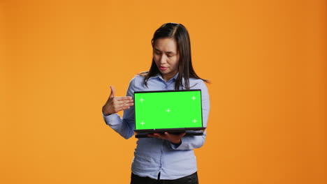 Confident-adult-showing-laptop-with-greenscreen