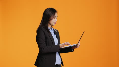 Businesswoman-browsing-sites-on-laptop-in-studio