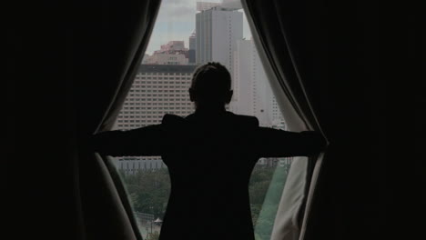 Woman-opening-curtains-and-looking-at-Hong-Kong