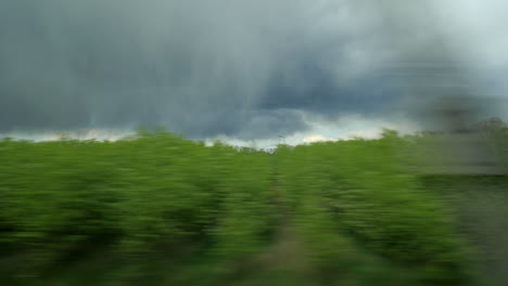 View-from-train-to-nature-landscapes-and-heavy-clouds