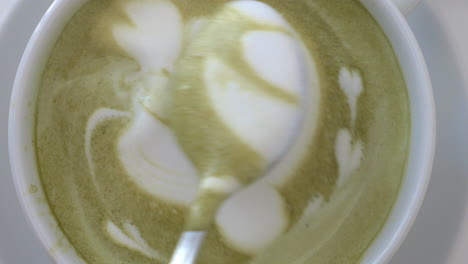 Close-up-shot-of-barista-finishing-cream-picture-on-latte-matcha