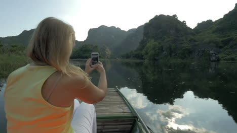 Touristin-Fotografiert-Mit-Handy-Während-Des-Bootfahrens-In-Trang-An,-Vietnam