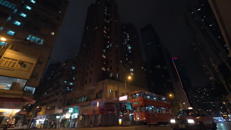 Seen-night-city-and-skyscrapers-with-a-busy-road-with-passing-double-decker-buses-and-cars