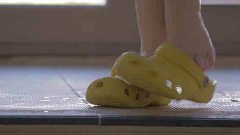 Child-putting-on-rubber-shoes-after-swimming-in-pool