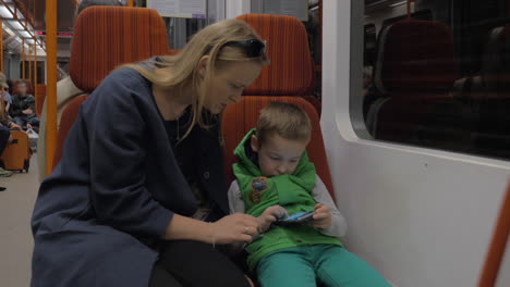 Child-and-mother-with-mobile-phone-in-subway-train