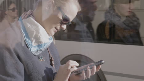 Young-woman-using-mobile-at-bus-stop