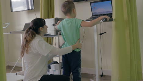 En-La-Clínica-Médica-Evexia-En-Un-Análisis-De-Sistema-Robótico-Y-Entrenamiento-Del-Equilibrio,-El-Médico-Entrena-A-Un-Niño-Pequeño-Para-Mantener-El-Equilibrio