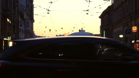 At-sunset-at-intersection-people-crossing-road-passing-cars