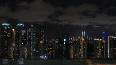 Vista-De-Una-Mujer-Nadando-En-La-Piscina-En-El-Techo-Del-Rascacielos-Contra-El-Paisaje-Nocturno-De-La-Ciudad-Kuala-Lumpur-Malasia