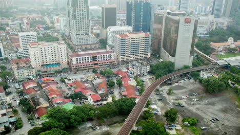 Vista-De-Lapso-De-Tiempo-A-Vista-De-Pájaro-De-Los-Ferrocarriles-A-Través-De-La-Carretera-Contra-El-Paisaje-De-La-Ciudad-Kuala-Lumpur-Malasia