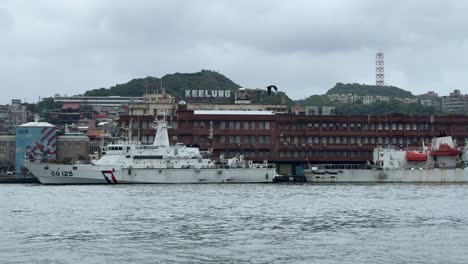 Cloudy-view-of-boats-docked-at-the-port-and-against-the-background-of-the-city-landmarks-and-iconic-Keelung-sign-in-Keelung-City,-Ren’ai-District,-Taiwan