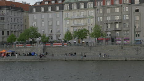 Vista-Desde-El-Barco-Que-Se-Mueve-Por-El-Río-Moldava-A-Lo-Largo-Del-Hotel-Residente-Estándar-Y-Terraplén-Praga-República-Checa