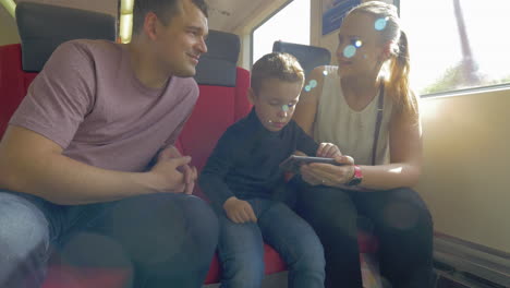 Family-with-child-traveling-by-train-and-using-cell