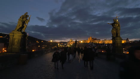 Los-Turistas-Caminan-Por-El-Puente-De-Carlos-Por-La-Noche-En-Praga.