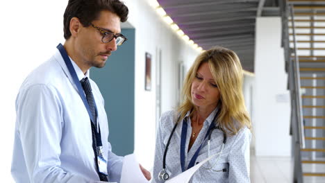 Male-And-Female-Doctor-Having-Meeting-In-Hospital-Corridor