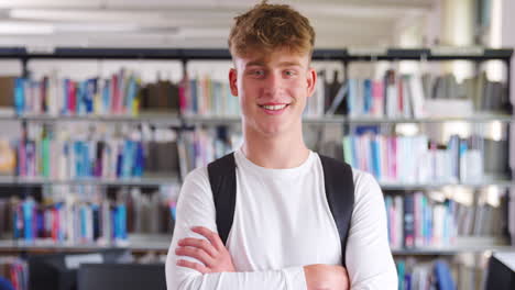 Portrait-Of-Male-Student-Standing-In-College-Library