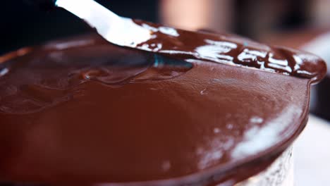 Nahaufnahme-Eines-Bäckers,-Der-Mit-Einem-Messer-Geschmolzene-Schokolade-Auf-Dem-Kuchen-Verteilt