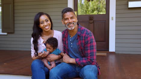 Portrait-Of-Parents-With-Baby-Son-Sitting-On-Steps-Of-House